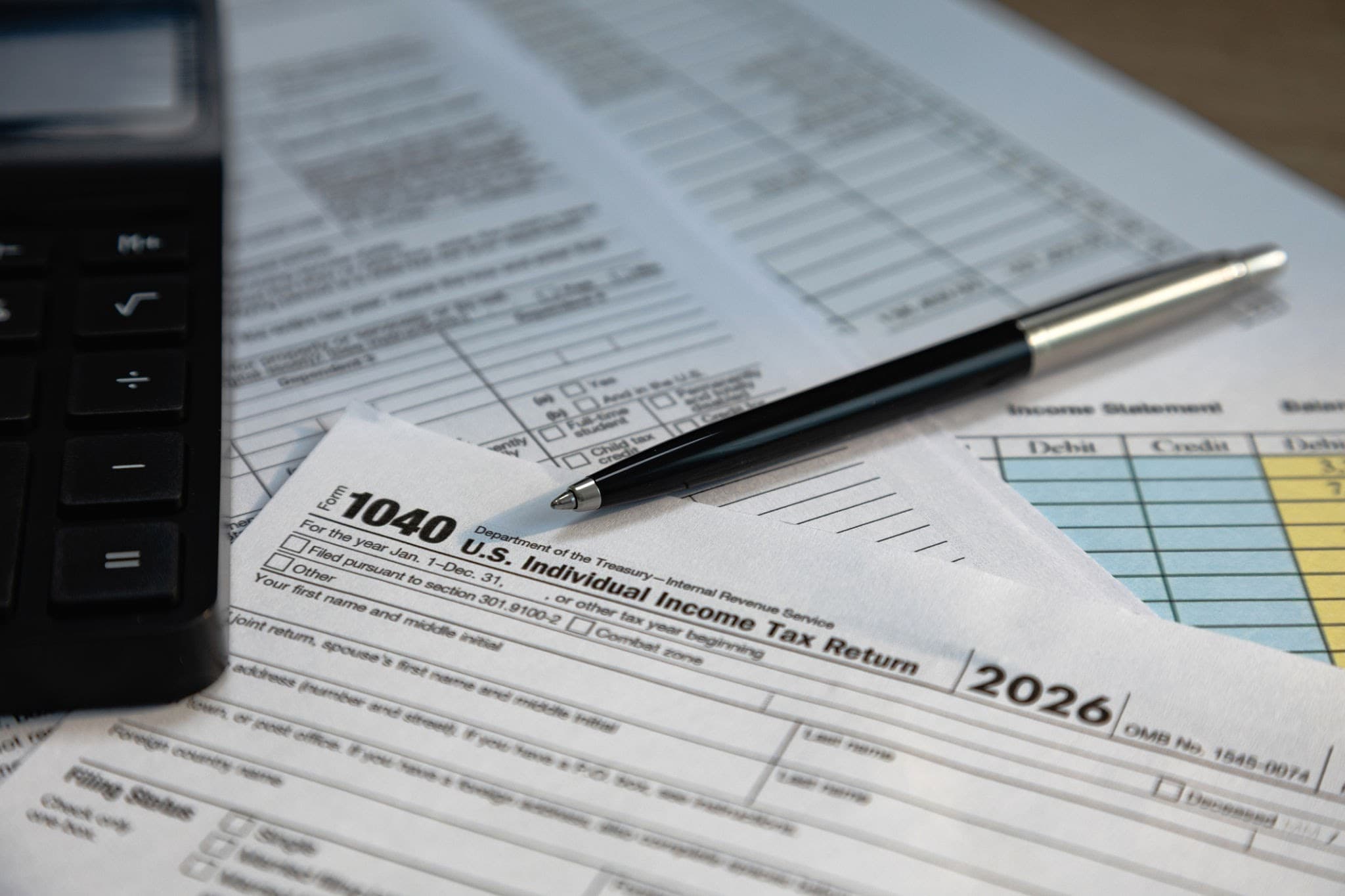 A US individual income tax return form beside a keyboard and pen on financial documents