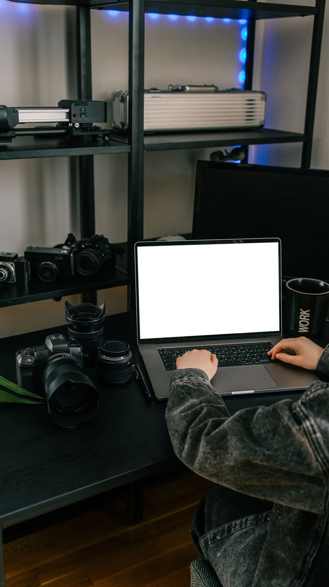 A creator typing on a laptop surrounded by professional camera and production equipment