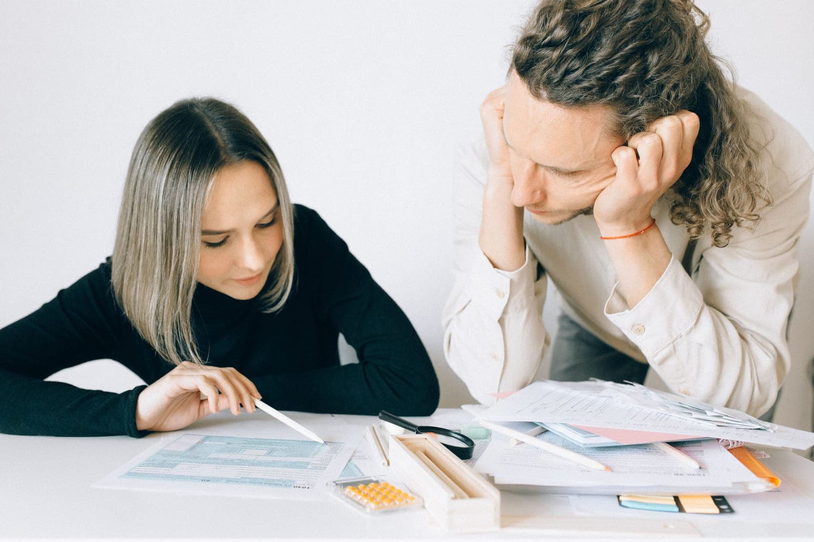 Two people looking worried as they go over numbers and financial paperwork at a desk